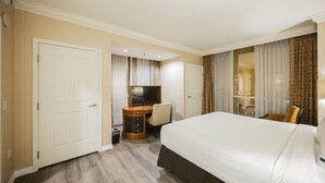 A hotel room with a bed, a desk with a chair, a television, and a mirror. - SVS: PH Floor One Bedroom | Balcony | Signature at MGM (Las Vegas)