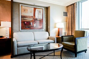 Ein Hotelzimmer mit einer Couch, einem Sessel, einem Couchtisch und einem Bild an der Wand.