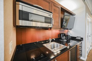 A modern kitchen with a built-in microwave, a stainless steel sink, and a coffee maker. - SVS: Studio | Signature at MGM (Las Vegas)