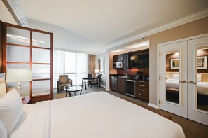 A hotel room with a large bed, a dining table with chairs, a kitchenette, and a separate bedroom area. - SVS: Studio | Signature at MGM (Las Vegas)