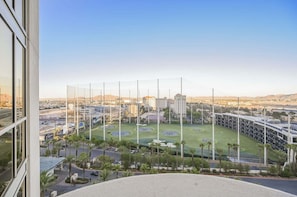 A view of a stadium with multiple seating tiers, surrounded by greenery and palm trees, with buildings in the background. - SVS: One Bedroom | Balcony | Signature at MGM (Las Vegas)