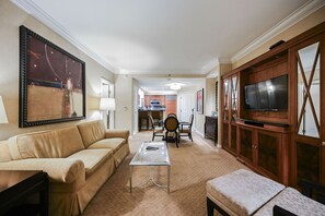 Ein Hotelzimmer mit Sofa, Couchtisch, Fernseher, Essbereich mit Stühlen und einer Küche im Hintergrund.