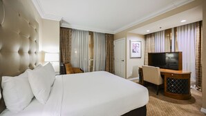 Een hotelkamer met een groot bed, een bureau met een televisie, een stoel en een deur.