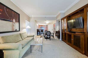 Ein Wohnzimmer mit Sofa, Couchtisch, Fernseher und Essbereich mit Stühlen und Tisch.