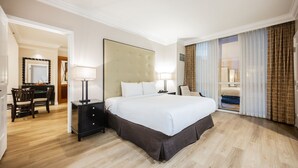 Une chambre d’hôtel avec un grand lit, un bureau avec une chaise, un miroir et une vue sur l’extérieur.