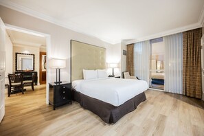 A hotel room with a large bed, a desk with a chair, a mirror, and a view of the outside. - SVS: Remodeled One Bedroom | Strip View Balcony | MGM Signature (Las Vegas)