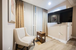 A room with a chair, a small table, a TV mounted on the wall, and a door. - Remodeled 1BD/2BA • Strip View • Balcony • No Resort Fee F14Q3 (Las Vegas)