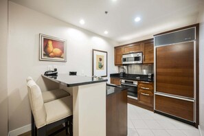 A modern kitchen with a central island, stainless steel appliances, and wooden cabinets. - SVS: Remodeled One Bedroom | Strip View Balcony | MGM Signature (Las Vegas)