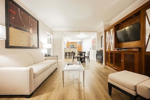 A living room with a sofa, coffee table, TV, and wooden cabinets. - Remodeled 1BD/2BA • Strip View • Balcony • No Resort Fee F14Q3 (Las Vegas)