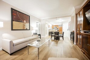 A modern living room with a sofa, coffee table, and dining area with chairs. - SVS: Remodeled One Bedroom | Strip View Balcony | MGM Signature (Las Vegas)