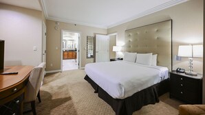 Quarto de hotel com cama, escrivaninha, cadeira, mesa de cabeceira e espelho.
