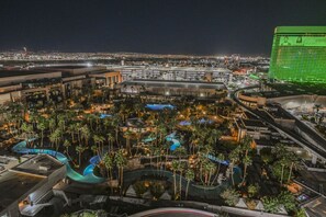 Um hotel com várias piscinas, palmeiras e um edifício grande ao fundo.