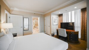 Hotelkamer met een groot bed, een televisie, een bureau met stoel, en een badkamer die door een open deur zichtbaar is.