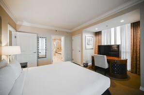 Camera d'albergo con un letto grande, una TV, una scrivania con una sedia e un bagno visibile attraverso una porta aperta.