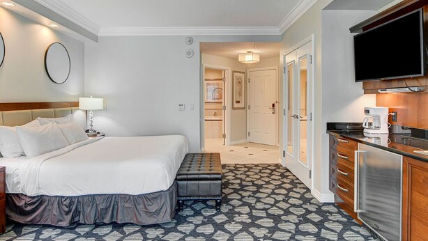 Ein Hotelzimmer mit Bett, Nachttisch, Lampe und Fernseher.