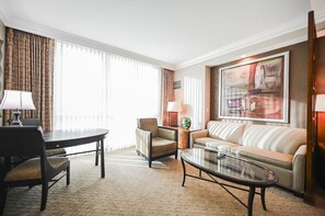 A hotel room with a dining table, two armchairs, a sofa, a coffee table, and a large abstract painting on the wall. - SVS: Studio | Signature at MGM (Las Vegas)