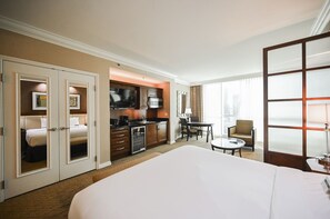 A hotel room with a large bed, a kitchenette, a dining area, and a view of the city. - SVS: Studio | Signature at MGM (Las Vegas)