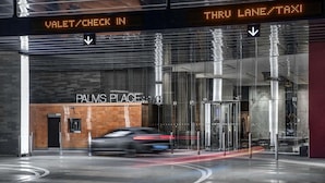 Ingresso di un edificio moderno con un cartello digitale che indica servizio di auto di lusso e area di passaggio per taxi.