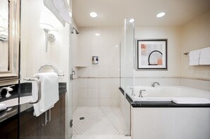 Een moderne badkamer met een douchecabine van glas, een ruime badkuip en een wastafel met spiegel en handdoekhouder.