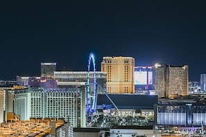A cityscape at night with illuminated buildings, including a prominent Ferris wheel and several high-rise hotels. - SVS: PH Floor Sphere Strip View Balcony | Signature at MGM (Las Vegas)