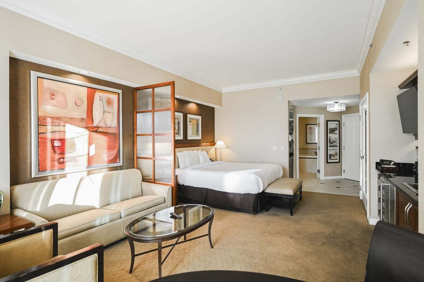 Une chambre d’hôtel comprenant un lit, un canapé, une table basse, une télévision et une kitchenette.