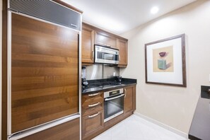 Eine Küche mit Holzausstattung, einer Mikrowelle, einem Herd und einem Backofen.