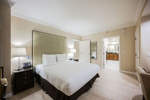Ein Hotelzimmer mit einem großen Bett, Nachttischen, einem Schminktisch und Blick ins Bad.