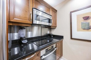 A compact kitchen with a built-in microwave, a blender, and a stovetop. - SVS: One Bedroom | Strip View Balcony | MGM Signature (Las Vegas)