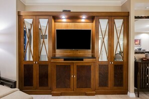A wooden entertainment center with a flat-screen TV, built-in shelves, and mirrored doors. - SVS: One Bedroom | Strip View Balcony | MGM Signature (Las Vegas)