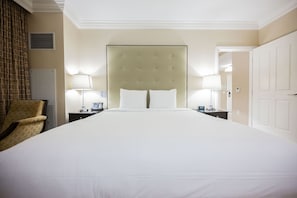 A hotel room with a large bed, two bedside tables with lamps, a chair, and a door. - SVS: One Bedroom | Strip View Balcony | MGM Signature (Las Vegas)