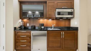 A kitchen with wooden cabinets, a built-in microwave, a dishwasher, and a flat-screen TV.