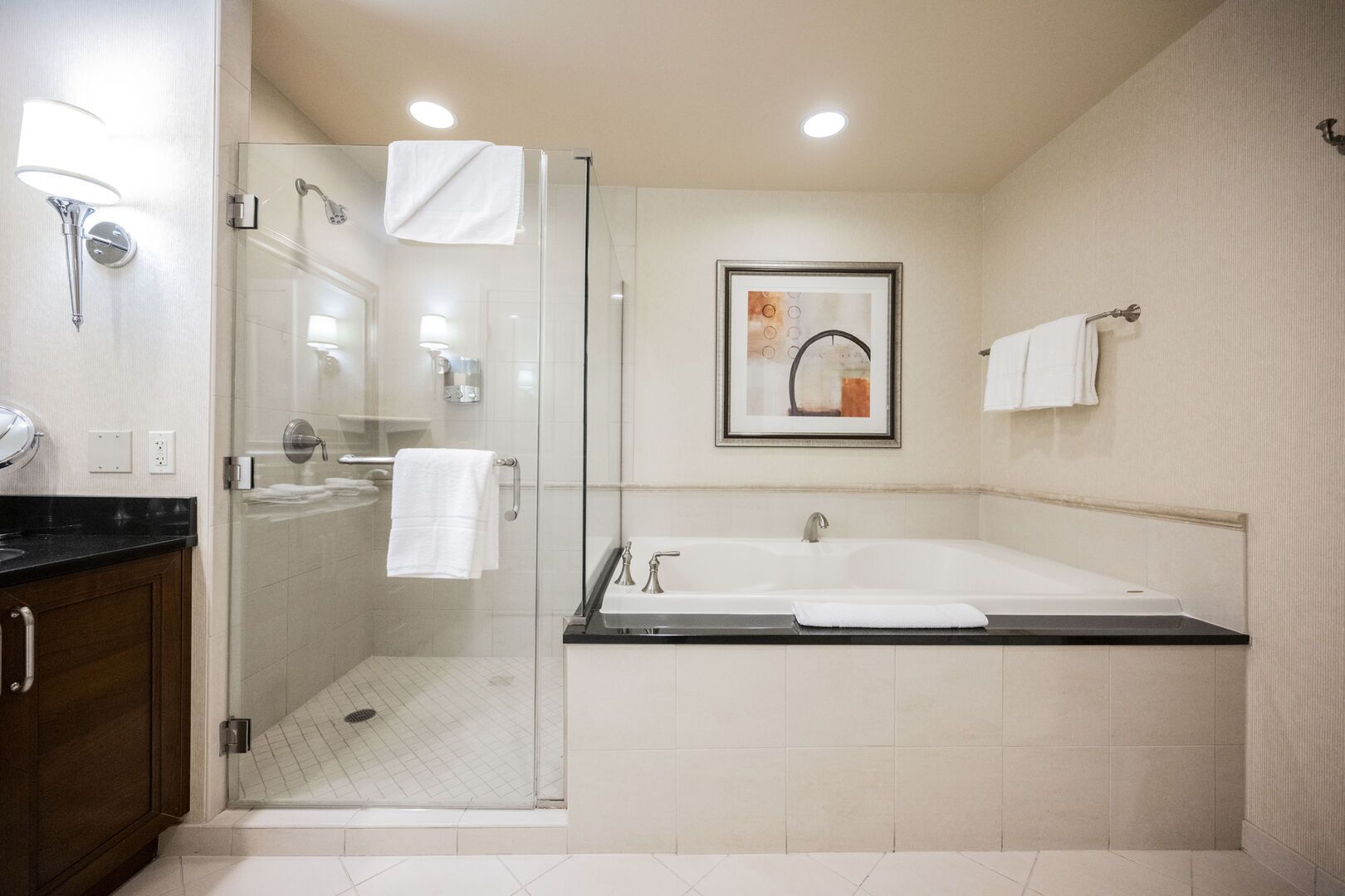 Une salle de bain moderne avec une douche à parois de verre, une grande baignoire et une œuvre d’art encadrée au mur.