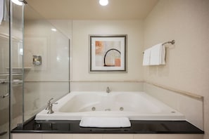 A bathroom with a large bathtub, a glass shower enclosure, a framed artwork on the wall, and a towel rack with towels. - SVS: Strip View Studio | Resort Pool & Gym | Signature at MGM (Las Vegas)
