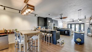 Uma cozinha moderna com uma ilha central, banquetas de bar e uma mesa de jantar.