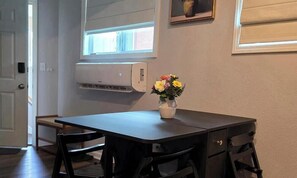 A room with a table, chairs, a vase with flowers, an air conditioning unit, and a window. - Ultra Clean 2BT w/2 Kings Near MCI and T-Mobile Center (Riverside)