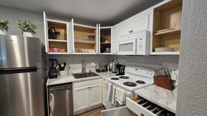 A modern kitchen with white cabinetry, stainless steel appliances, and a built-in wine cooler.