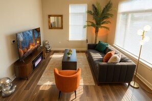 A modern living room with a flat-screen TV, a sofa, a coffee table, and a floor lamp.