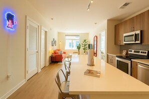 A modern kitchen with a central island, wooden cabinets, and a microwave.