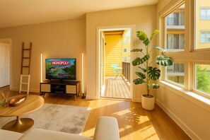 Un salón con televisor, una planta en maceta y vistas a un balcón.