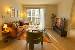Un salon avec un canapé, une table basse, un téléviseur et une plante.