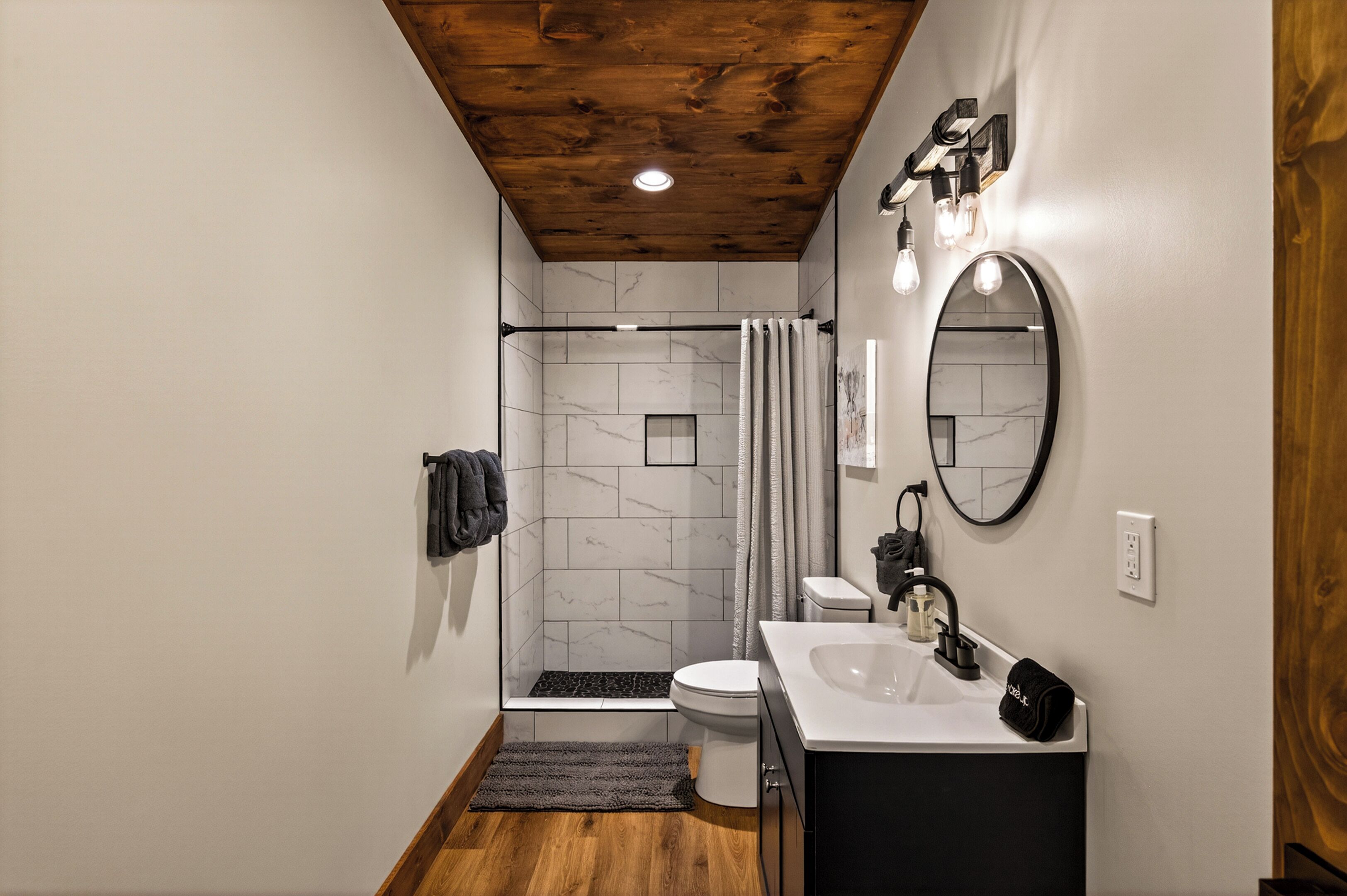 Un baño moderno con ducha, inodoro, lavamanos y espejo.