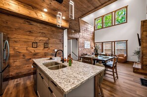 Eine Küche mit Holzwänden, Granit-Arbeitsplatten und einem Essbereich mit Tisch und Stühlen.