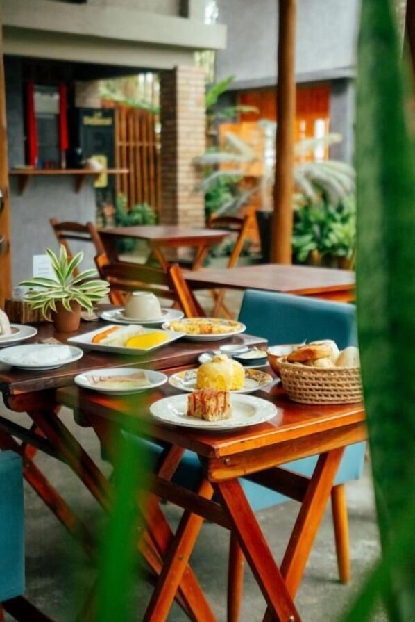A dining area with tables and chairs, plates with food, and a basket of bread.