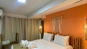 A hotel room with a bed, a bedside table, a wall-mounted lamp, and a small refrigerator. - Jimbaran Pousada & Bistrot (Maragogi)