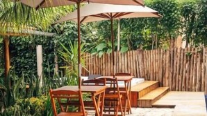 A wooden deck with outdoor furniture and a large umbrella. - Jimbaran Pousada & Bistrot (Maragogi)