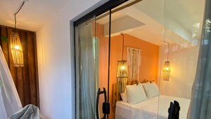 A modern bedroom with a glass door, a bean bag, a bed, and pendant lights. - Jimbaran Pousada & Bistrot (Maragogi)