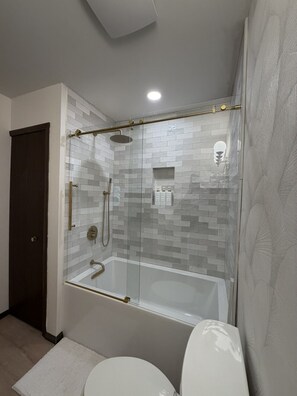 A modern bathroom with a glass-enclosed shower, a white bathtub, and a toilet. - Modern retreat near Lake Michigan and Coast Guard Park (Spring Lake)