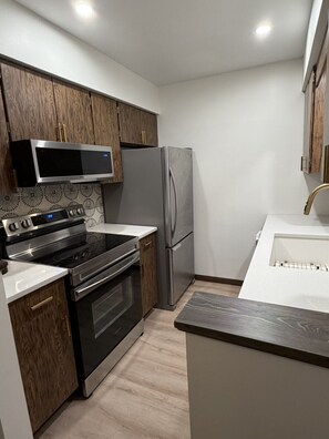 A kitchen with a stove, oven, microwave, refrigerator, and wooden cabinets. - Modern retreat near Lake Michigan and Coast Guard Park (Spring Lake)