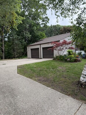 Eine Garage mit Wohnhof, einer Betonbefestigung, umgeben von Bäumen und einem gepflegten Rasen.