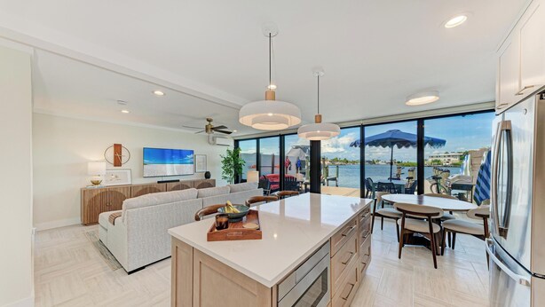 A modern kitchen with a large island, dining area, and a view of the sea.